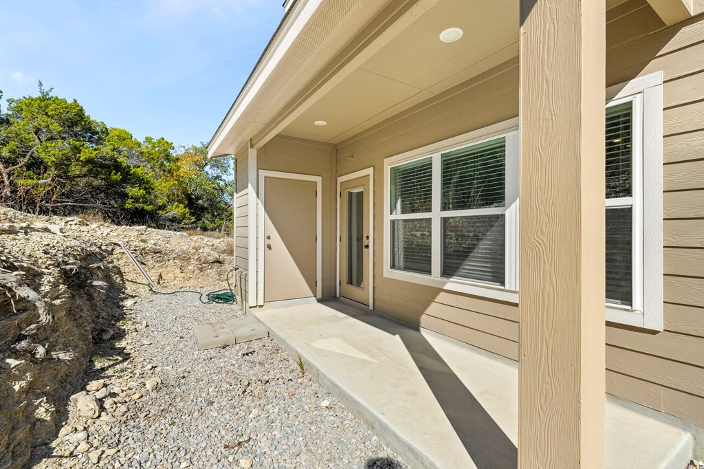 the front porch of a home with a door and a gravel driveway
