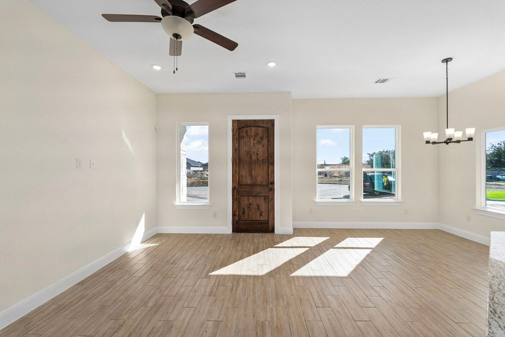 an empty living room with a ceiling fan and windows