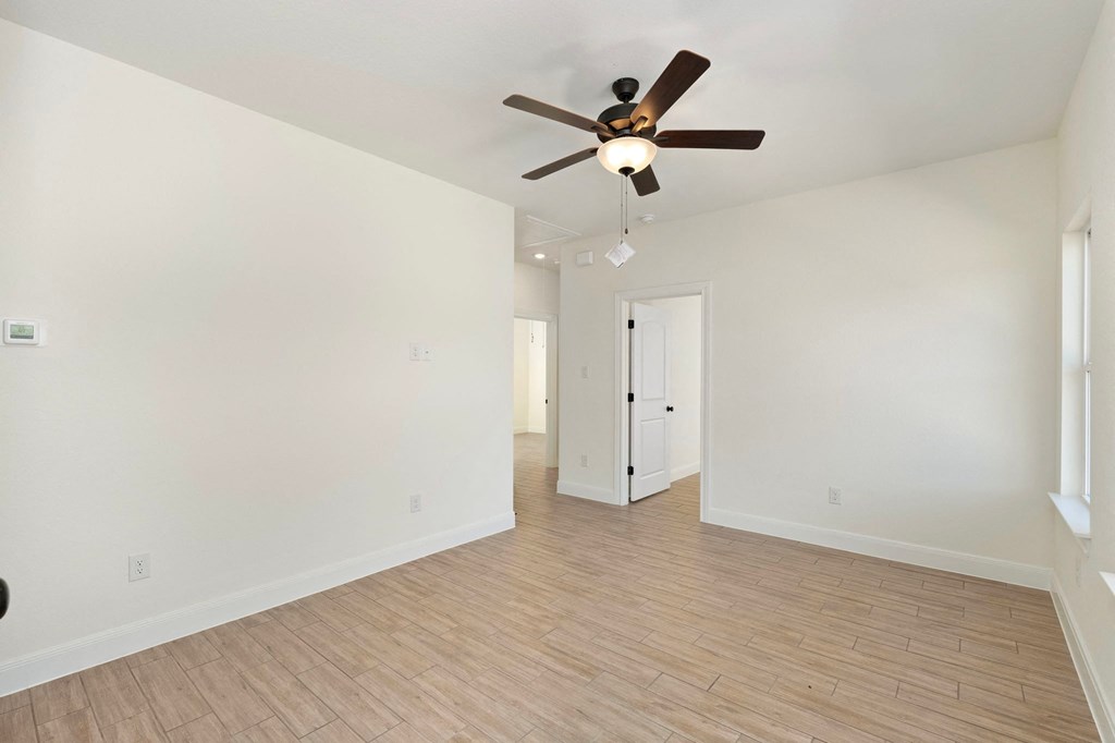 an empty living room with a ceiling fan and white walls