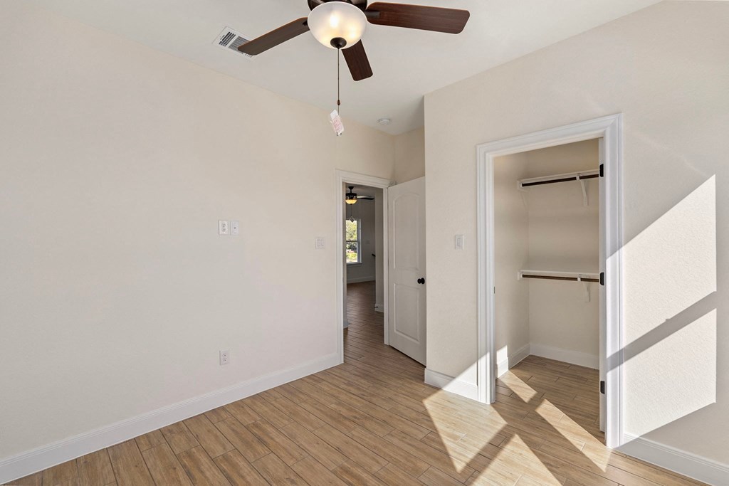 a living room with a ceiling fan and a hallway to a closet