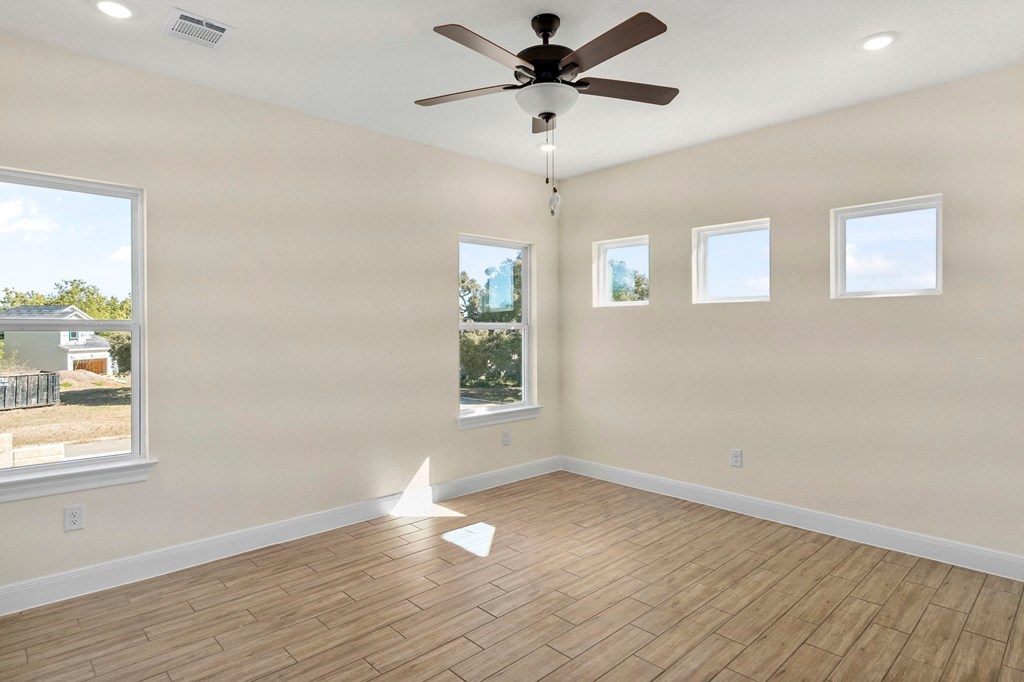 an empty living room with a ceiling fan and a wood floor