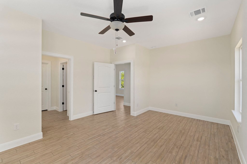 an empty living room with a ceiling fan and hardwood floors