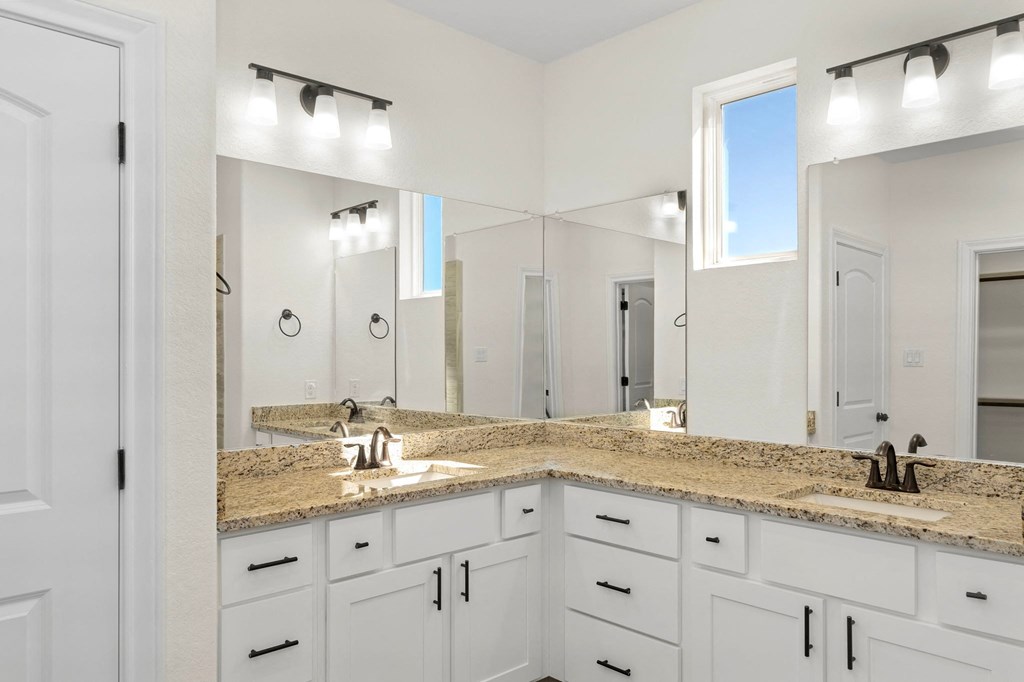 a bathroom with white cabinets and granite counter tops