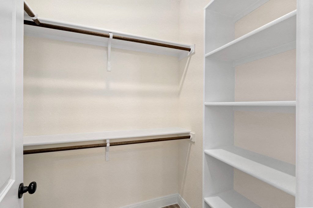 a walk in closet with empty shelves and a white closet door