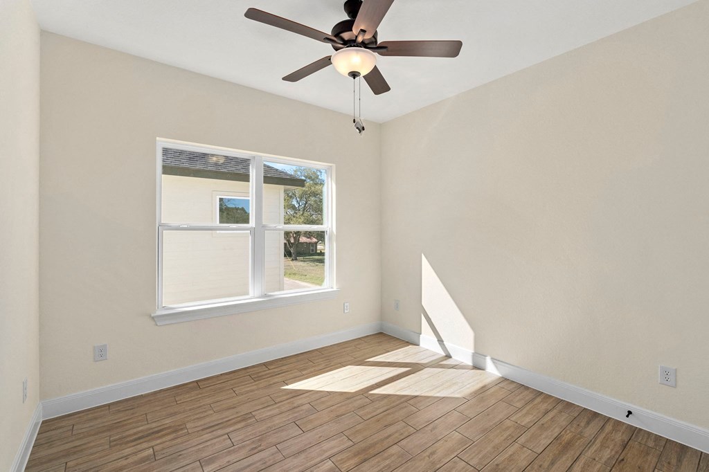 an empty living room with a ceiling fan and a window