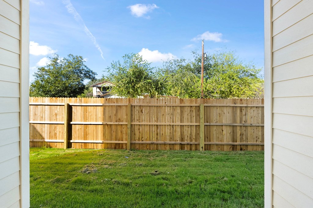 a backyard with a wooden fence and a green lawn