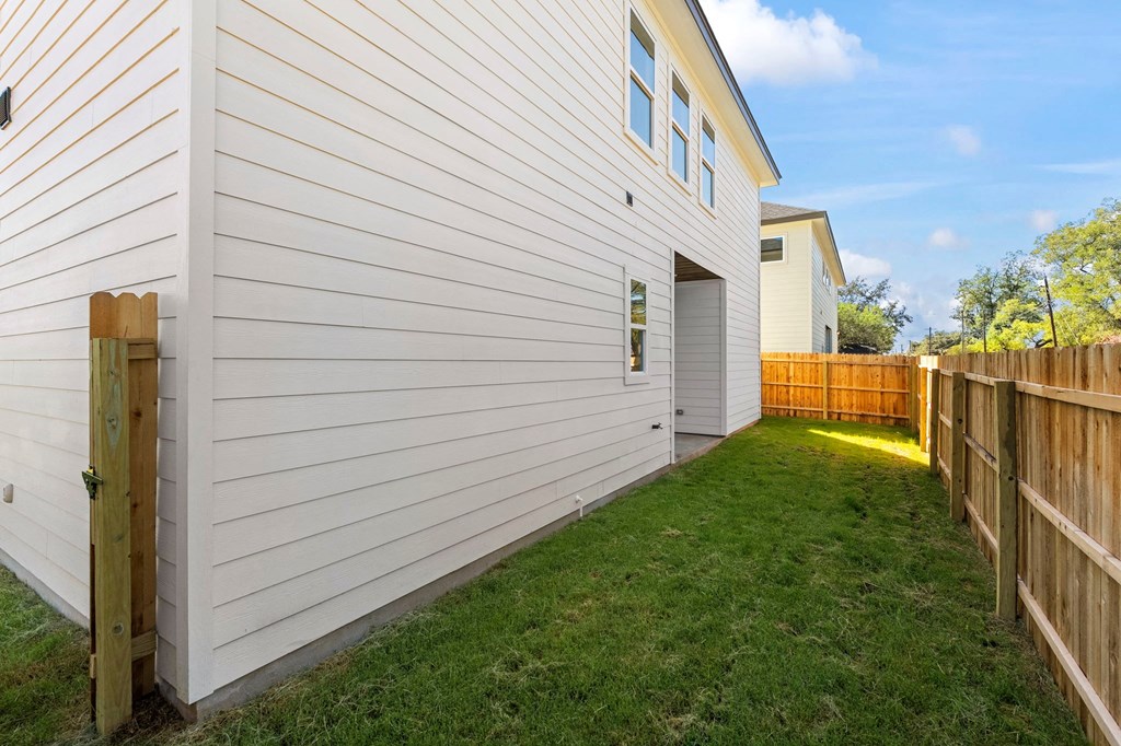 a backyard with a white house and a wooden fence