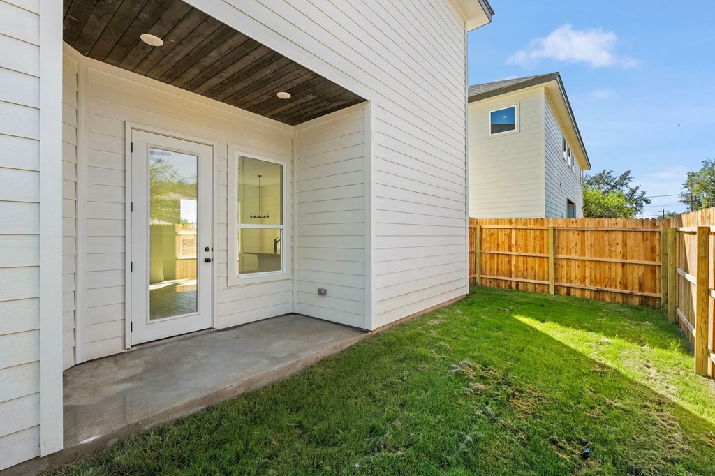 the back of a white house with a patio and a fence