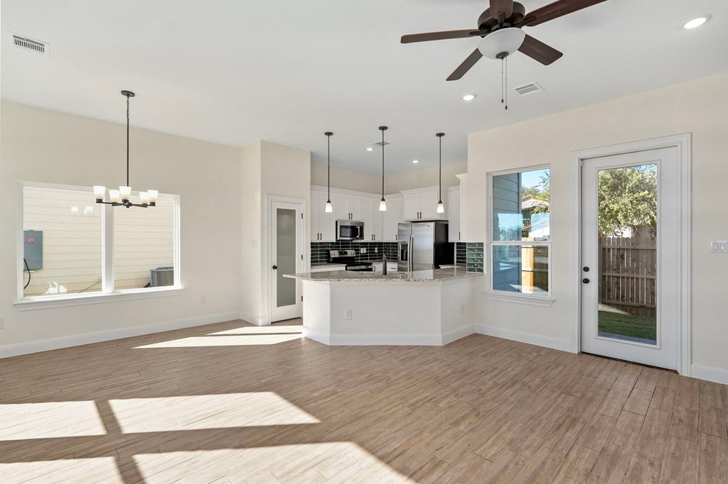 an open living room with a kitchen and a ceiling fan
