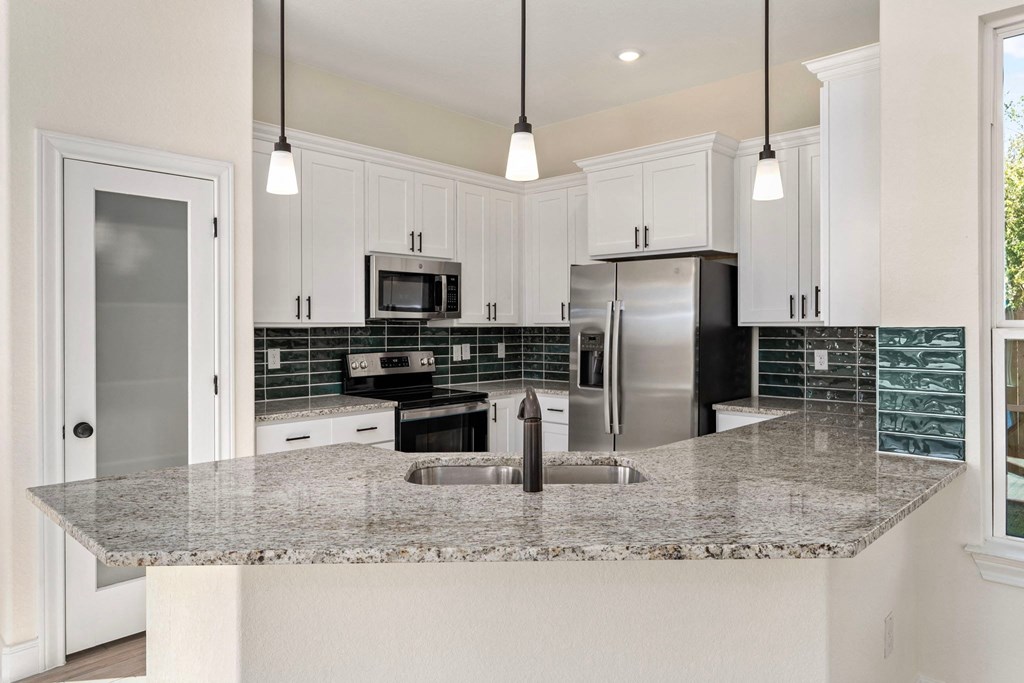 a kitchen with white cabinets and a granite counter top