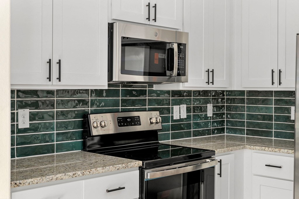 a kitchen with white cabinets and a stove and a microwave