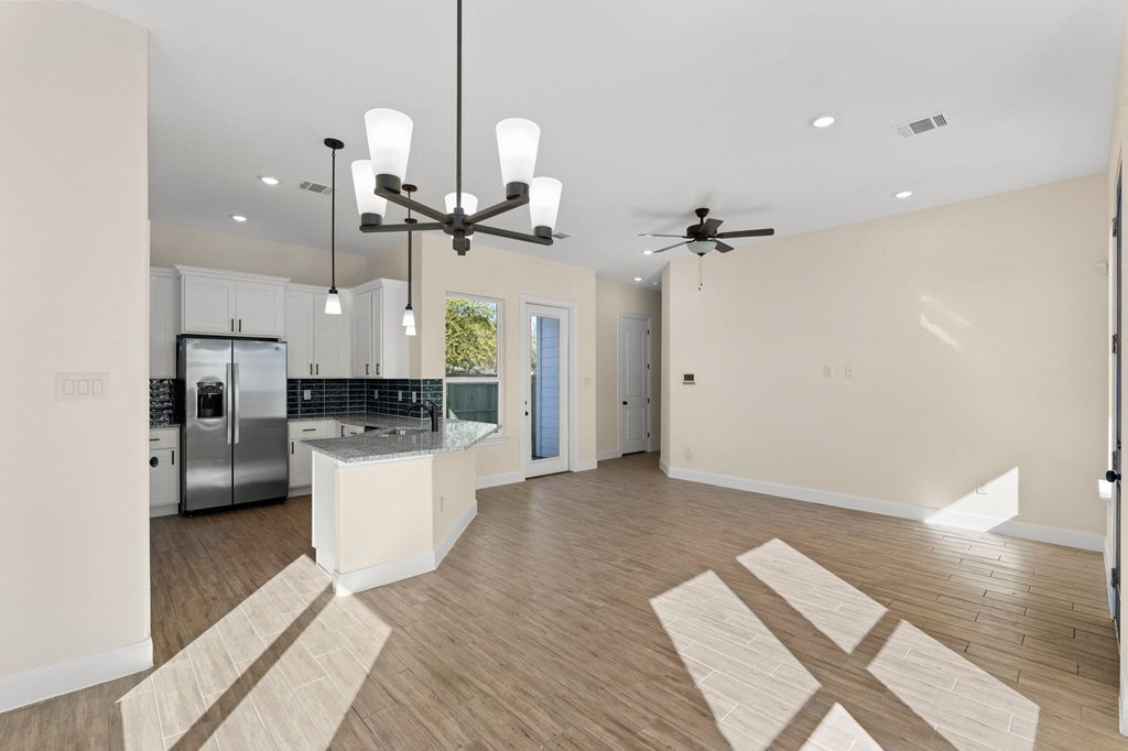 a kitchen and living room with white walls and wood floors