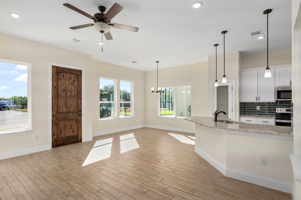 an empty living room with a kitchen and a ceiling fan