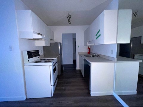 an empty kitchen with white cabinets and a stove