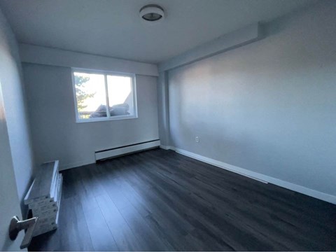 an empty room with wooden floors and a window
