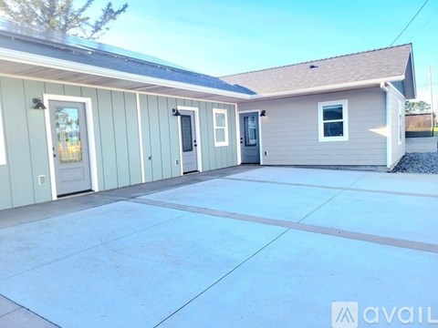 A house with a grey roof and a white door is available for rent.