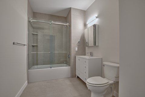A white bathroom with a toilet, sink, and shower.