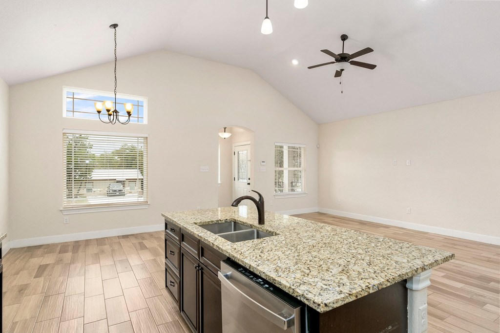 an empty kitchen with a granite counter top and a sink