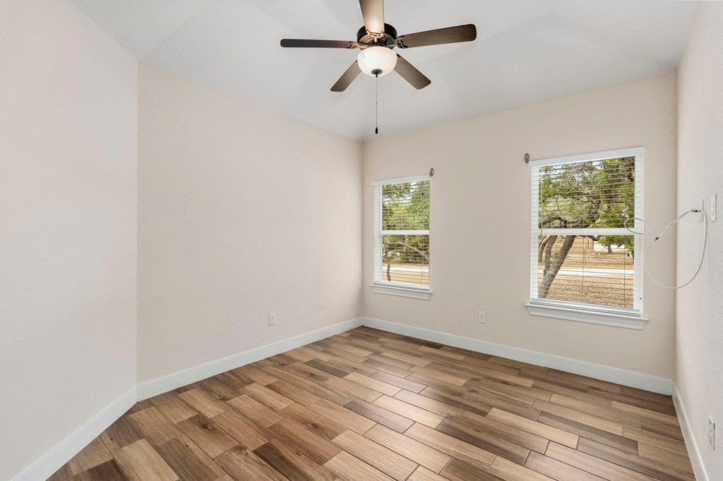an empty living room with a ceiling fan and a window