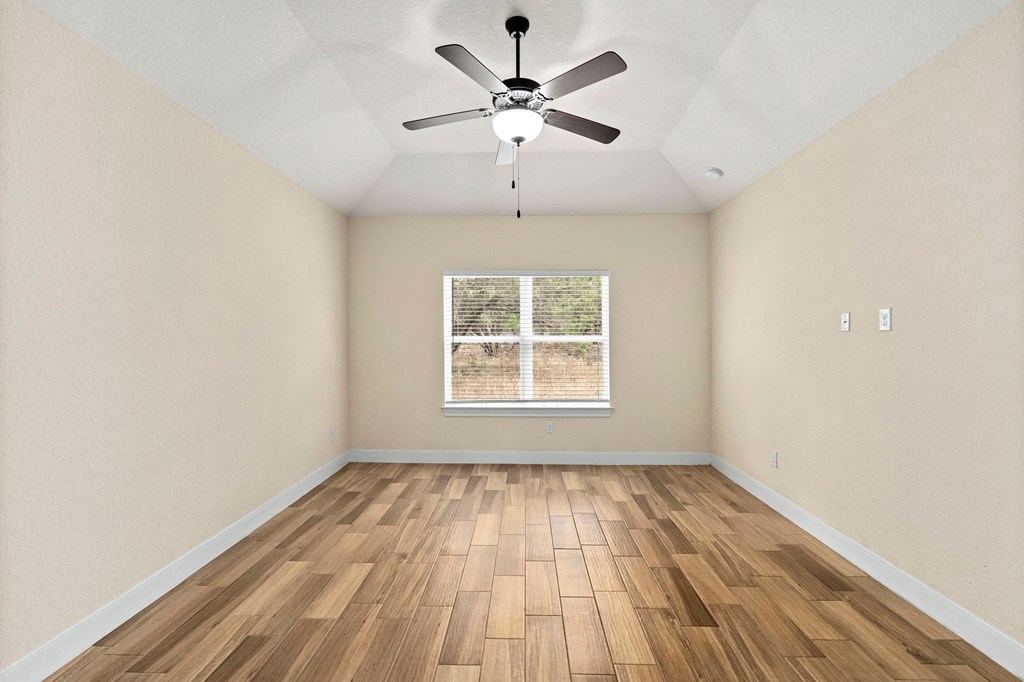the spacious living room with hardwood floors and a ceiling fan
