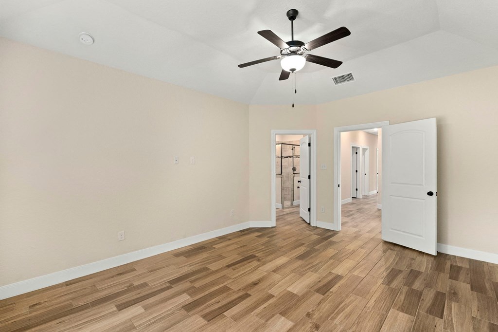 an empty living room with a ceiling fan and hardwood floors