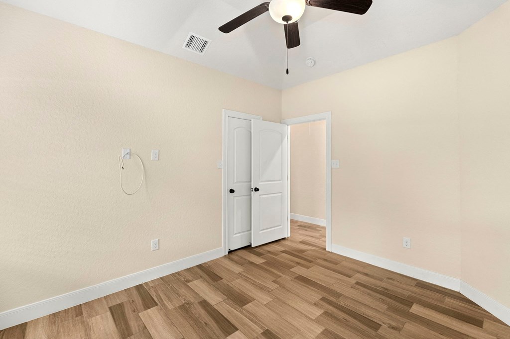 an empty bedroom with a ceiling fan and a closet