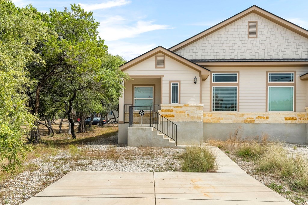 the front of a house with trees and a sidewalk