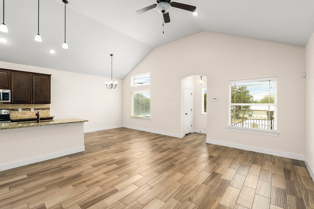 an open living room with a kitchen and a ceiling fan