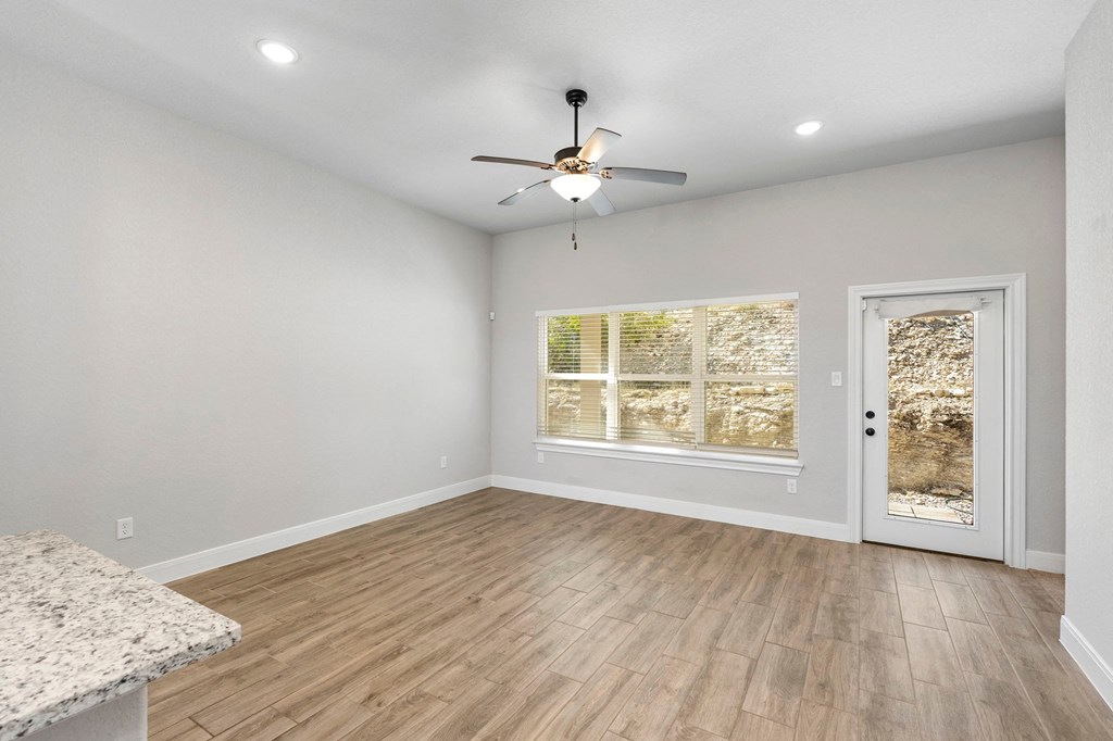 an empty living room with a ceiling fan and a window