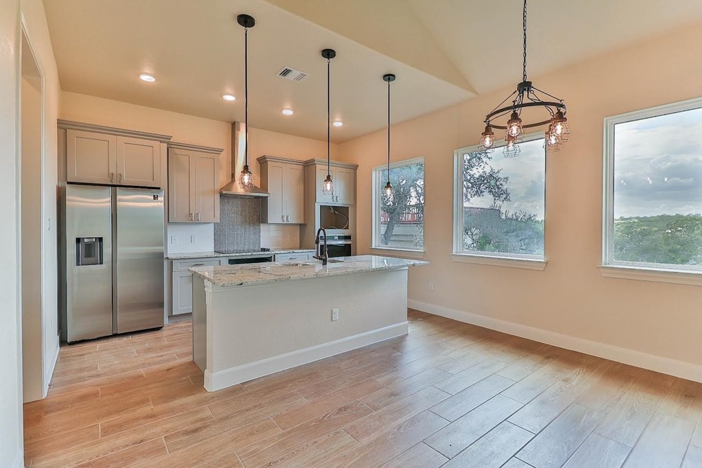 a kitchen with a large island and a stainless steel refrigerator
