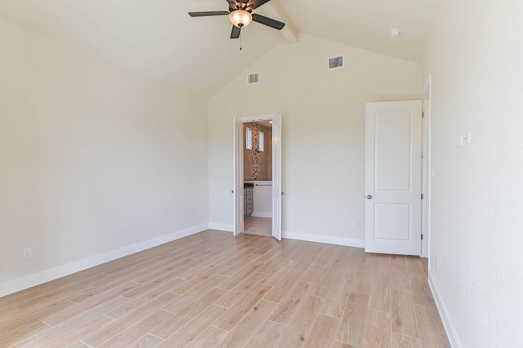 an empty living room with a ceiling fan and a door to a bathroom