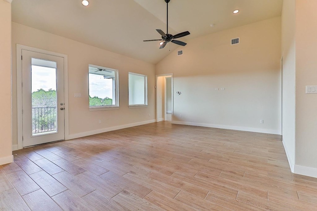 a empty living room with a ceiling fan and a door