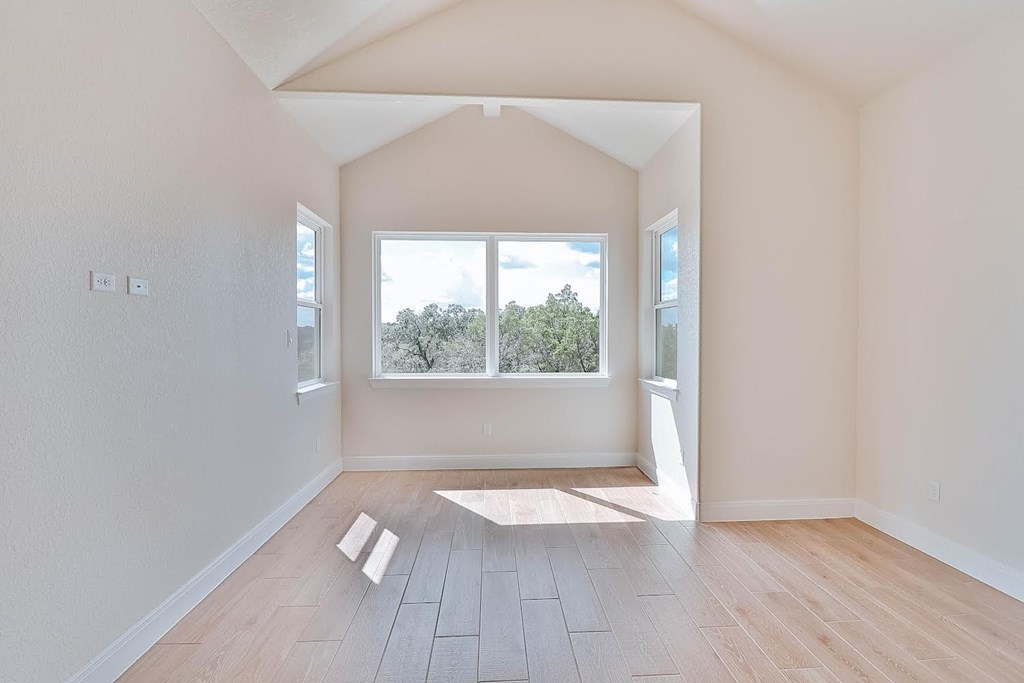 an empty living room with a large window and wooden floors