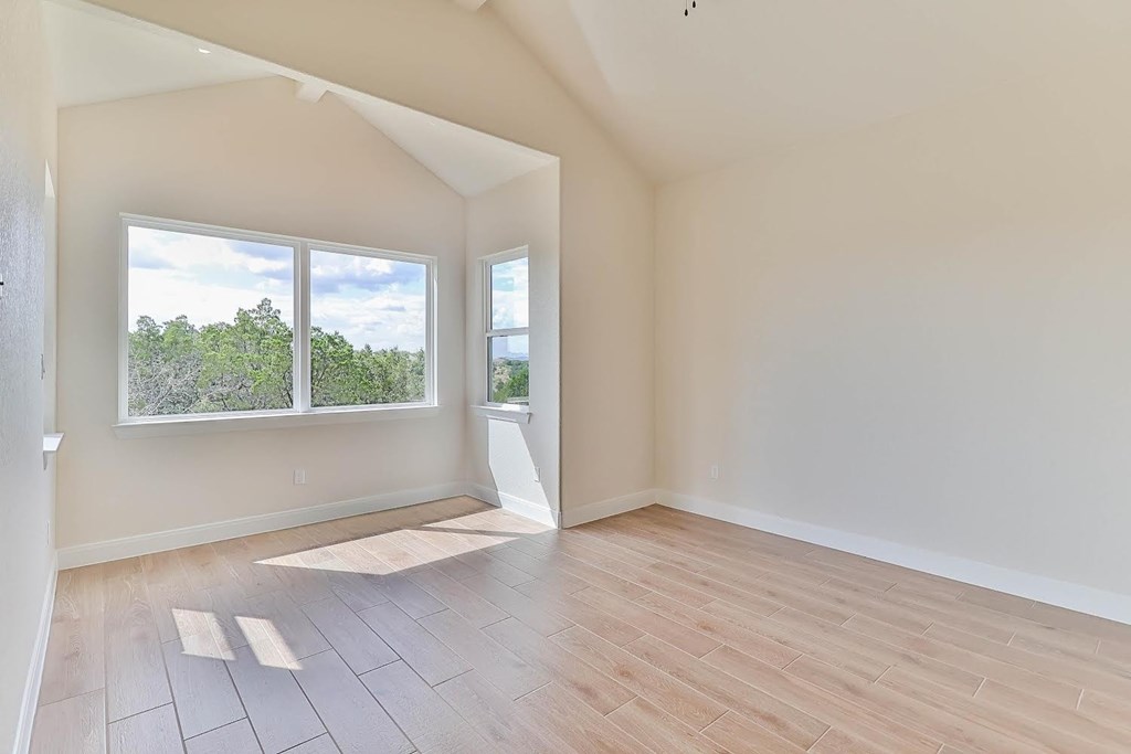 an empty living room with a large window and wooden floors