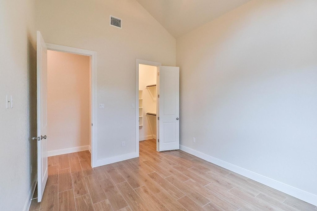 a bedroom with a door open to a bathroom and a closet