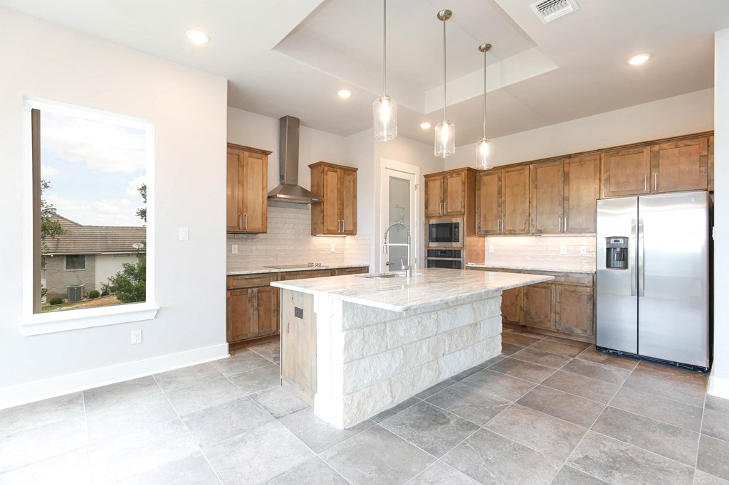 a large kitchen with wooden cabinets and a marble counter top