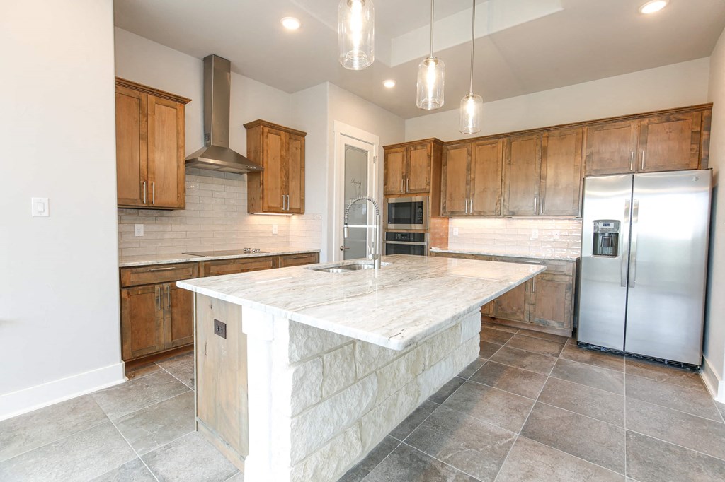 a kitchen with a marble counter top and a stainless steel refrigerator