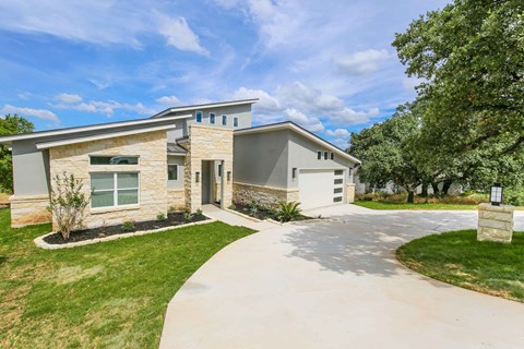 a house with a driveway and trees in front of it