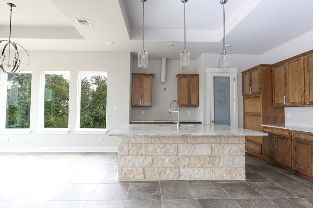 a large kitchen with a marble island and wooden cabinets