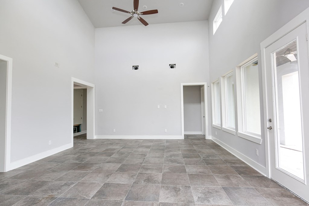 an empty living room with white walls and a ceiling fan