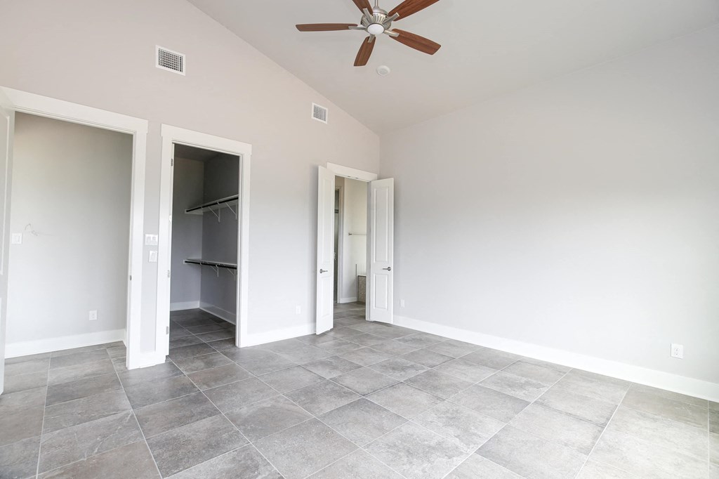 an empty living room with a ceiling fan and a closet