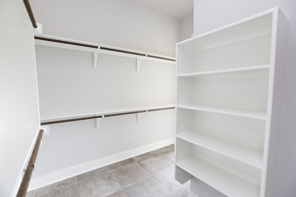 a walk in closet with white shelves and a white closet door
