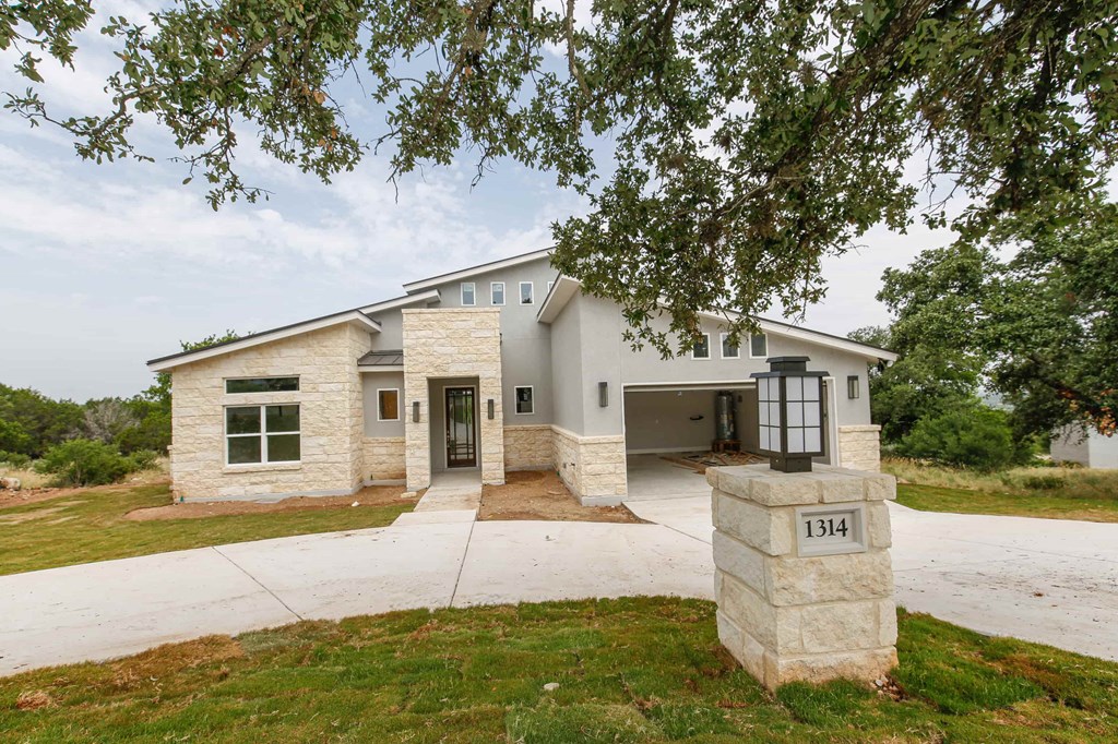 a white and tan house with a driveway and a tree