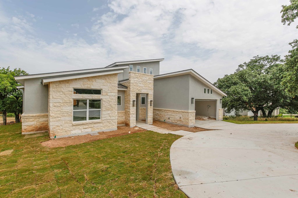 a house with a concrete driveway and a stone building with trees