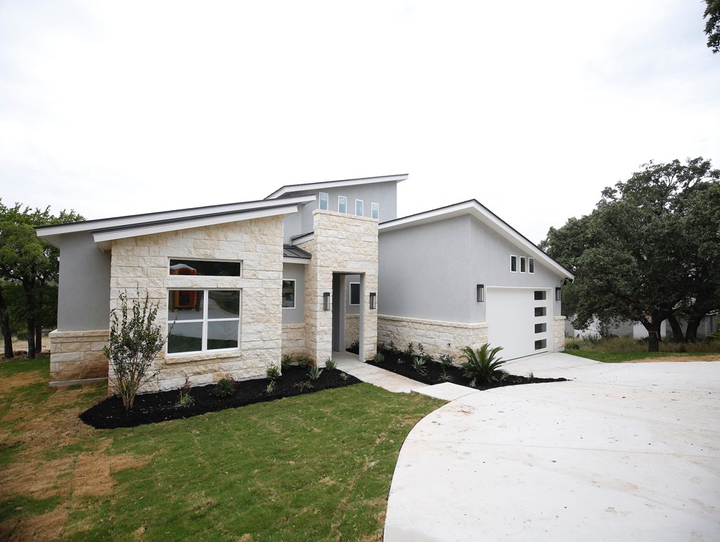 a white and gray house with a driveway and lawn