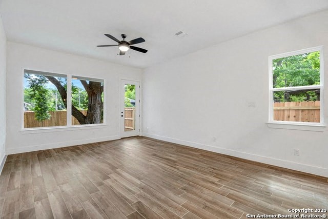 an empty living room with wood floors and a ceiling fan