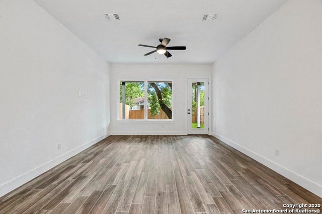 an empty living room with a ceiling fan and a window