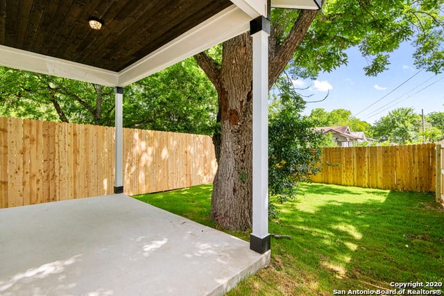 a covered porch with a tree and a wooden fence