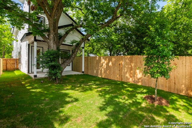 the backyard of a house with a fence and a tree