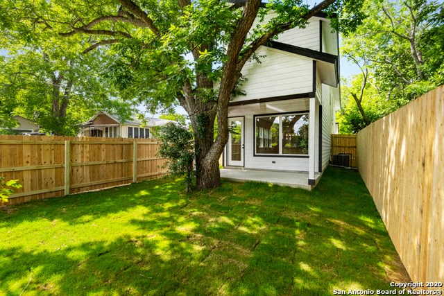 the backyard of a house with a tree and a fence
